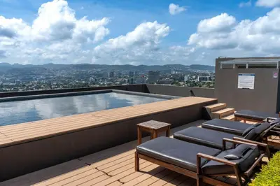 a balcony with chairs and a swimming pool on a building at Exclusive Apartment with Pool & Rooftop in El Salvador in San Salvador