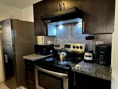 a kitchen with a stove and a refrigerator at Exclusive Apartment with Pool & Rooftop in El Salvador in San Salvador