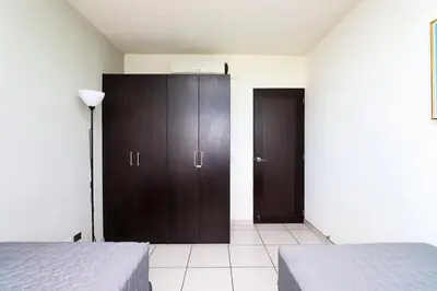 a bedroom with two beds and a brown cabinet at Exclusive Apartment with Pool & Rooftop in El Salvador in San Salvador