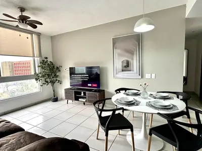 a living room with a table and chairs and a tv at Exclusive Apartment with Pool & Rooftop in El Salvador in San Salvador