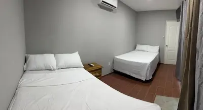 two beds in a small room with white sheets at Container house in La Esmeralda