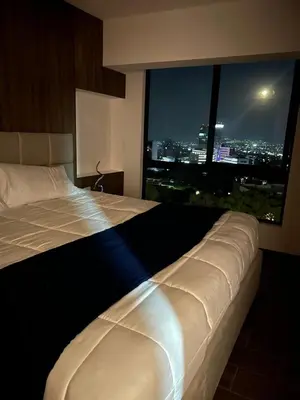 a bed in a hotel room with a large window at View of The Capital, Escalon SV in San Salvador