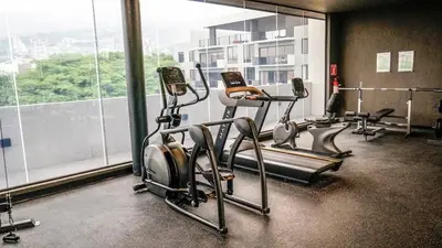 a gym with several cardio machines and a large window at View of The Capital, Escalon SV in San Salvador