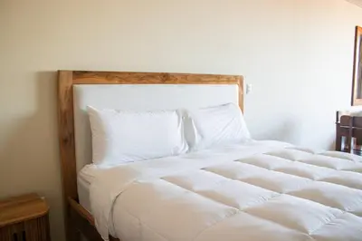 a bed with white sheets and pillows in a room at Spacious Apartment with Balcony in El Zonte