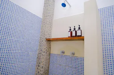 a blue tiled bathroom with bottles on a shelf at Casa K59 - Walk to Beach in Taquillo