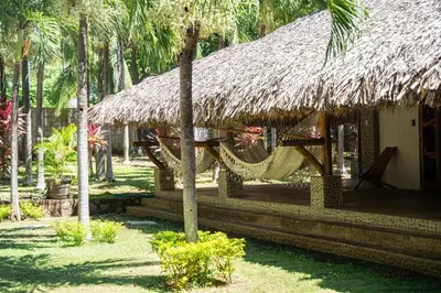 a resort with a hammock and a hut with palm trees at Casa K59 - Walk to Beach in Taquillo