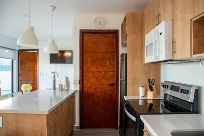 a kitchen with wooden cabinets and a wooden door at Luxury Apartment- View- Pool- La Libertad Surfcity in La Libertad