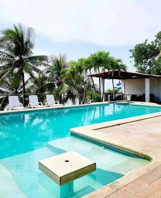 a swimming pool at a resort with chairs and palm trees at El Tunco Beachfront Surf City Spot in Tamanique