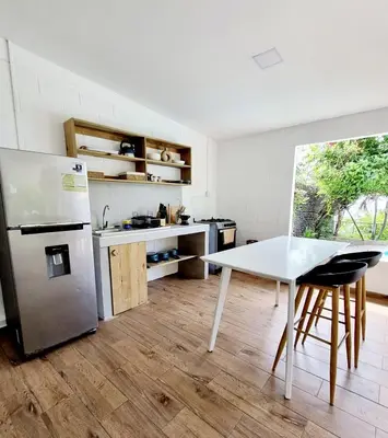 a kitchen with a white table and a refrigerator at El Tunco Beachfront Surf City Spot in Tamanique