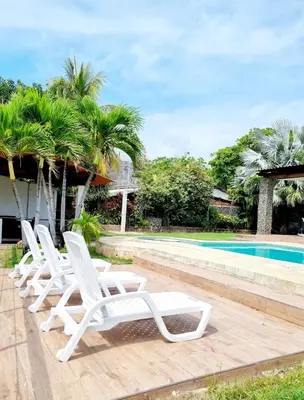 a row of white lounge chairs next to a swimming pool at El Tunco Beachfront Surf City Spot in Tamanique