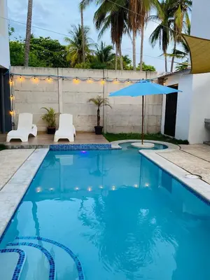 a swimming pool with two white chairs and an umbrella at via costera 1 in La Libertad