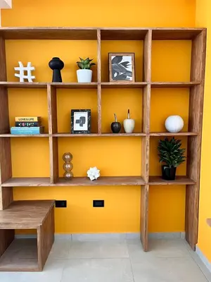 a yellow wall with wooden shelves and a bench at via costera 1 in La Libertad