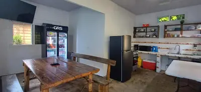 a kitchen with a wooden table and a refrigerator at California Beach, Teotepeque, La Libertad in Las Victorias