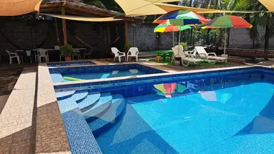 a blue swimming pool with umbrellas and chairs at California Beach, Teotepeque, La Libertad in Las Victorias