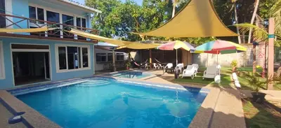 a swimming pool with umbrellas and a house at California Beach, Teotepeque, La Libertad in Las Victorias