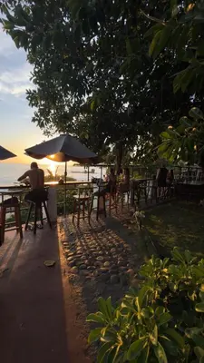 a group of people sitting at tables near the water at Hotel Casa Miramar in Tamanique