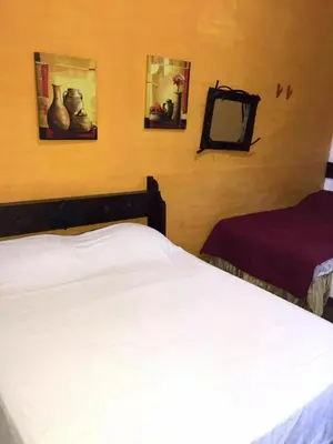 a bedroom with a white bed and two pictures on the wall at Hotel Villa Santo Domingo in Concepción de Ataco