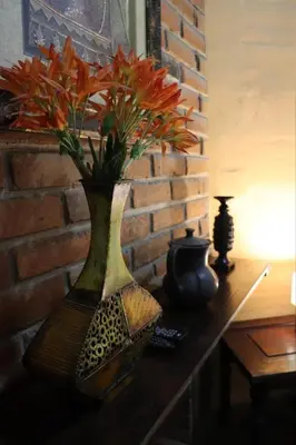 a vase with flowers on a table next to a brick wall at Hotel Villa Santo Domingo in Concepción de Ataco