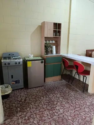 a kitchen with a stove and a counter with two chairs at Room Buganvilia in Nahuizalco