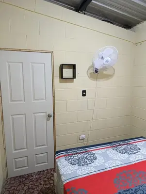 a bedroom with a door and a fan on the wall at Room Buganvilia in Nahuizalco