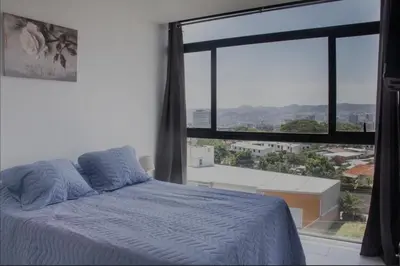 a bedroom with a bed and a large window at The Balcony of the City in San Salvador