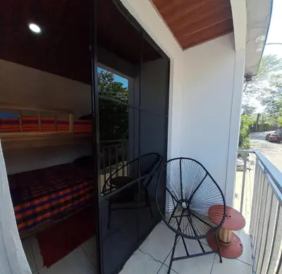 a room with a bed and a chair on a balcony at Zonte Rooftop Studio Apartment w Terrace-AC-Wif-BBQ in El Zonte
