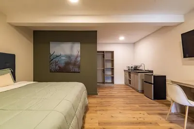a bedroom with a bed and a desk and a kitchen at Lora Loca Inn in El Zonte