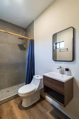 a bathroom with a toilet and a sink and a mirror at Lora Loca Inn in El Zonte