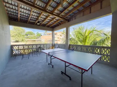 a ping pong table on a balcony with chairs at Lora Loca Inn in El Zonte