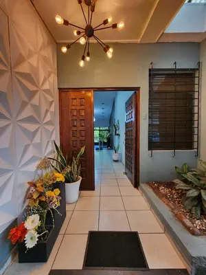 a hallway of a home with a ceiling fan and flowers at Mochila Urban1 in San Salvador