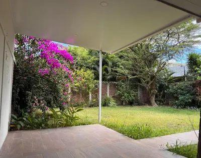 an open patio with a large bush with pink flowers at Mochila Urban1 in San Salvador