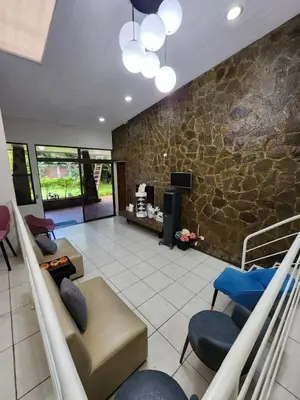 a living room with couches and chairs and a stone wall at La Mochila Urbana3 in San Salvador