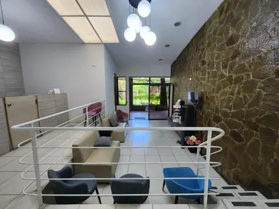 a lobby with a staircase with blue chairs and a stone wall at La Mochila Urbana3 in San Salvador