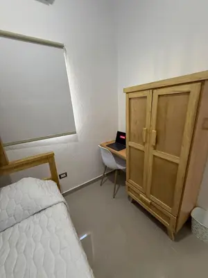 a bedroom with a bed and a desk and a wooden cabinet at Maadi-Tiny House-Los Ausoles in Ahuachapán