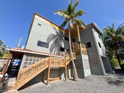 a house with a wooden staircase and a palm tree at 2 Bedroom Apartment with full beds and bunk beds in El Zonte