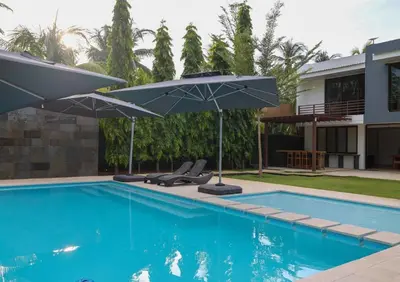 a swimming pool with two chairs and umbrellas next to a house at Then open space allowed for us to enjoy a big gathering in El Zapote