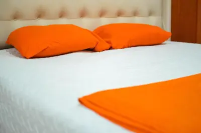 two orange pillows on top of a white bed at Suite 607 Ciudad jardín San Miguel A in San Miguel