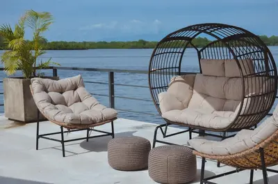 two wicker chairs and ottomans sitting on a deck at Astra Beach Club & Resort in Marcelino