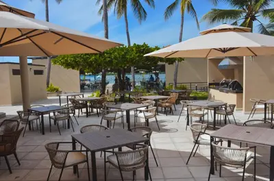 an outdoor patio with tables and chairs and umbrellas at Astra Beach Club & Resort in Marcelino