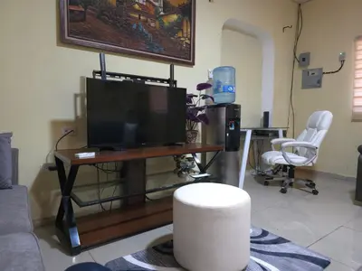 a living room with a tv and two chairs at Beautiful and comfortable house in Sonsonate