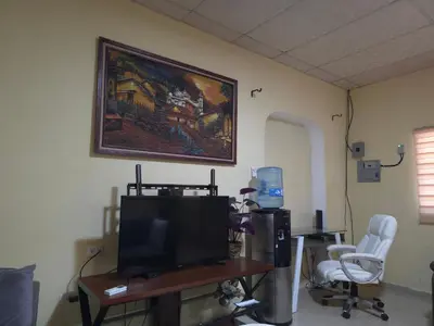 a living room with a tv and two chairs at Beautiful and comfortable house in Sonsonate