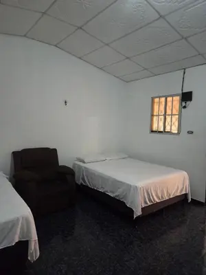 a room with a bed and a chair and a window at Hotel Ohana in San Juan Talpa
