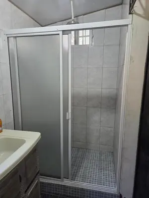 a shower with a glass door next to a sink at Hotel Ohana in San Juan Talpa