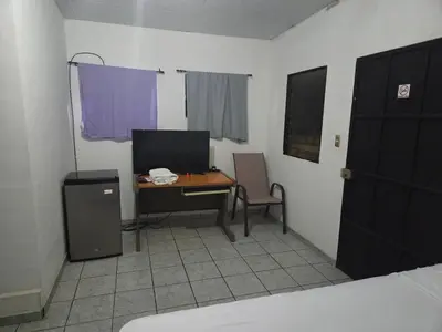 a room with a desk and a table with a computer at Hotel Ohana in San Juan Talpa