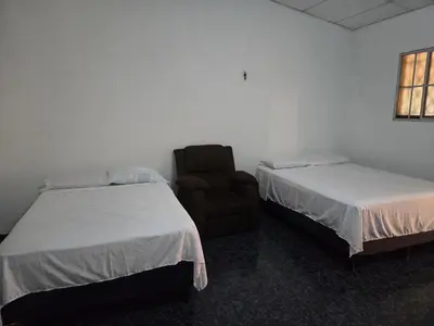 a room with two beds and a chair in it at Hotel Ohana in San Juan Talpa