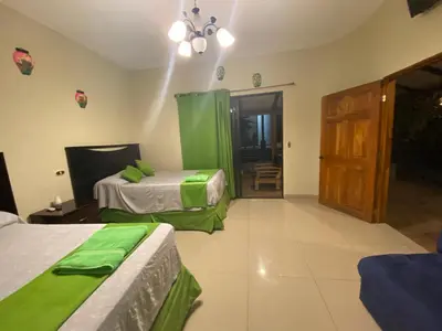 a room with two beds with green sheets and a door at Termales El Paraíso in Turín