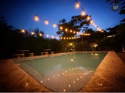 a swimming pool at night with lights and picnic tables at Termales El Paraíso in Turín