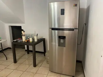 a stainless steel refrigerator in a kitchen with a table at La Casa de Lourdes in Colón