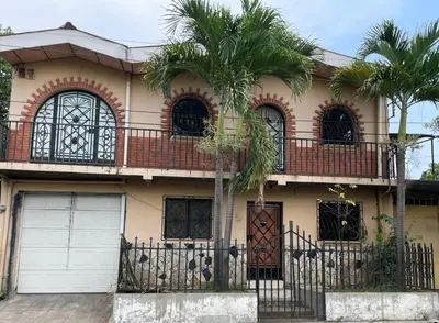 a house with two palm trees in front of it at La Casa de Lourdes in Colón