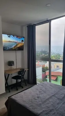 a bedroom with a desk and a large window at Apartamento centrico con vista exepcional al volcan de San Salvador in San Salvador
